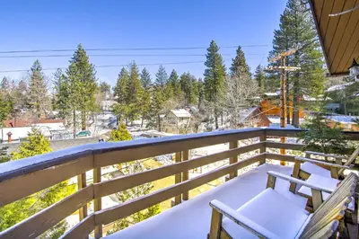 a snowy balcony with two chairs on a wooden railing at Cabin with Mtn Views and Deck, 5 Min To Arrowbear Lake! in Arrowbear Lake