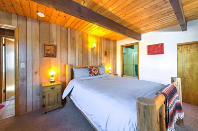 a bedroom with a bed and a wooden wall at Cabin with Mtn Views and Deck, 5 Min To Arrowbear Lake! in Arrowbear Lake
