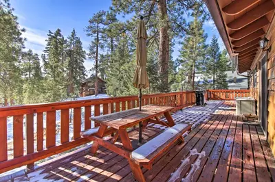 a wooden deck with a table and an umbrella at Walk to Lake Rustic Home with Deck in Fawnskin in Fawnskin