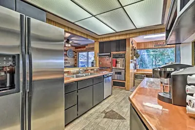 a kitchen with stainless steel appliances and wooden cabinets at Expansive Retreat with Deck, Game Room and Lake Views! in Lake Arrowhead