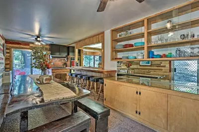 a kitchen with wooden cabinets and a bar with stools at Expansive Retreat with Deck, Game Room and Lake Views! in Lake Arrowhead