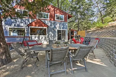 a table and chairs in front of a blue house at Expansive Retreat with Deck, Game Room and Lake Views! in Lake Arrowhead