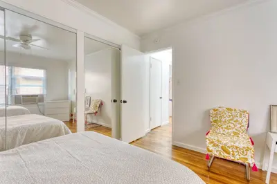 a white bedroom with two beds and a chair at New Beach Jewel Bungalow in Long Beach