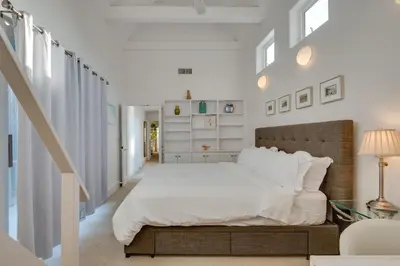 a white bedroom with a large bed and a staircase at Beachfront Malibu House with Sauna and Ocean-View Deck in Malibu
