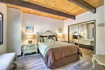a bedroom with a large bed and a mirror at Bikes and Game Room Lovely Lake Arrowhead Home! in Lake Arrowhead