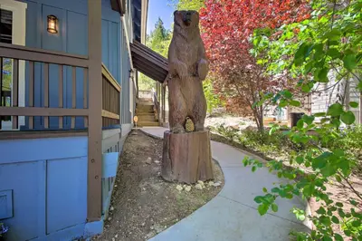 a statue of a bear sitting on a stump next to a house at Bikes and Game Room Lovely Lake Arrowhead Home! in Lake Arrowhead