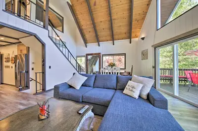 a living room with a blue couch and a table at Bikes and Game Room Lovely Lake Arrowhead Home! in Lake Arrowhead