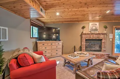 a living room with a red couch and a fireplace at Spacious Pine Mtn Club Cabin with Game Room and Deck in Pine Mountain Club