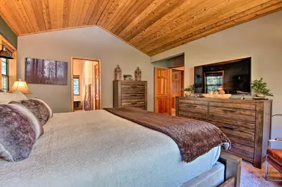 a bedroom with a large bed and a television at Spacious Pine Mtn Club Cabin with Game Room and Deck in Pine Mountain Club