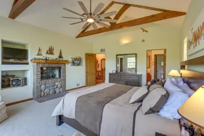 a bedroom with a large bed and a fireplace at Luxe Lake Arrowhead Home with Deck, 3 Mi to Village! in Lake Arrowhead
