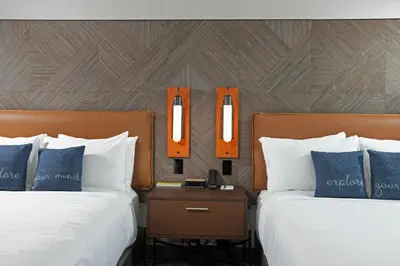 two beds in a hotel room with orange mirrors at The Glenmark, Glendale, a Tribute Portfolio Hotel in Glendale
