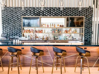 a bar with three stools in front of a counter at The Glenmark, Glendale, a Tribute Portfolio Hotel in Glendale