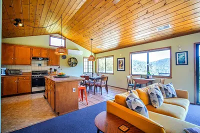 a kitchen and living room with a couch and a table at The Atomic Squirrel Lodge Lake Gregory Getaway! in Crestline
