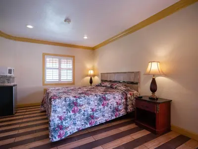 a bedroom with a bed and a table with a lamp at Parkside Inn in Long Beach