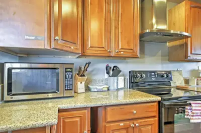 a kitchen with wooden cabinets and a microwave at 3 Mi to Dtwn Dining! Long Beach Condo with Balcony in Long Beach