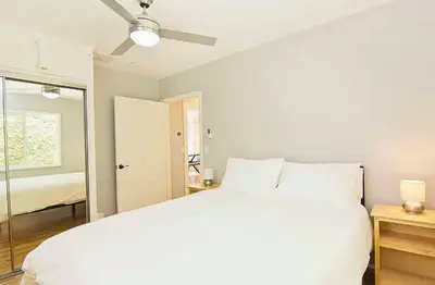 a bedroom with a white bed with a ceiling fan at Hollywood's Garden Paradise at World Artists Living in Los Angeles