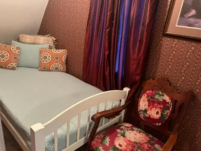 a baby crib with a bed and a chair at Arrowhead Lake Inn in Lake Arrowhead