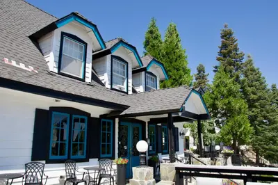 a house with chairs and tables in front of it at Arrowhead Lake Inn in Lake Arrowhead