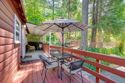a patio with a table and chairs and an umbrella at Vintage Snow White Cottage about 2 Miles to Village! in Lake Arrowhead