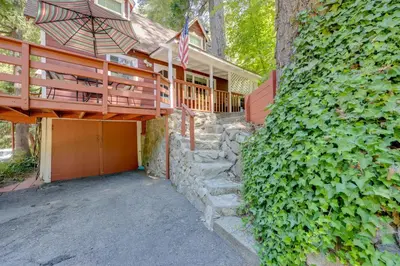 a house with a staircase leading up to a porch with an umbrella at Vintage Snow White Cottage about 2 Miles to Village! in Lake Arrowhead