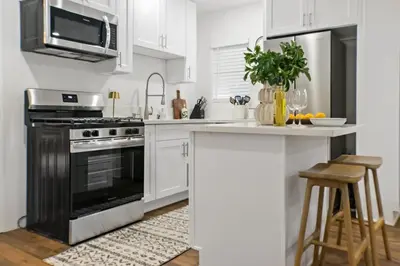 a kitchen with white cabinets and a black oven at Newly Renovated Gem Mins to Convention Center, Beaches and Downtown LB A in Long Beach