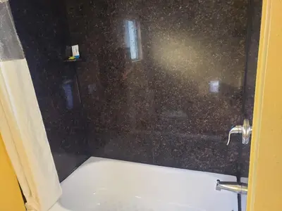 a shower with a glass door with a bath tub at Providencia Motel in Burbank
