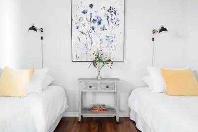 two beds with white sheets and a table with a vase of flowers at Historic Hm Mins to Beach, Convention Ctr Parking LB E in Long Beach