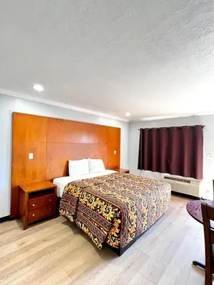 a bedroom with a bed with a wooden headboard at Aqua Inn Motel in El Monte