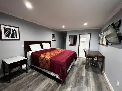a bedroom with a bed and a desk and a computer at Aqua Inn Motel in El Monte