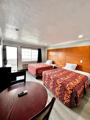 a hotel room with two beds and a table at Aqua Inn Motel in El Monte