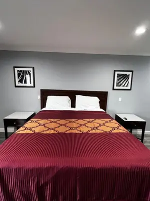 a bedroom with a large red bed with two tables at Aqua Inn Motel in El Monte