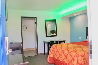 a bedroom with a bed and a desk and a mirror at Arlington Motel in Long Beach