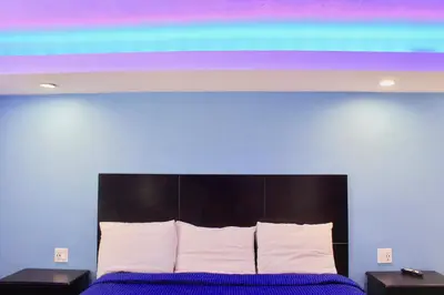 a bedroom with a blue wall and a bed with white pillows at Arlington Motel in Long Beach