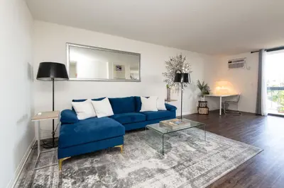 a living room with a blue couch and a table at Skyline Views 1-Bedroom with Balcony and Pool in Los Angeles