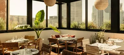 a restaurant with tables and chairs and large windows at The Hoxton, Downtown LA in Los Angeles