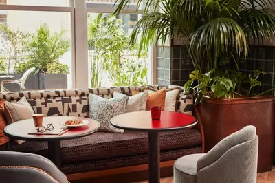 a living room with a couch and two tables at The Hoxton, Downtown LA in Los Angeles