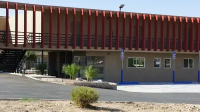 a building with a red roof and a parking lot at Apple Valley Hotel & Lodge in Apple Valley