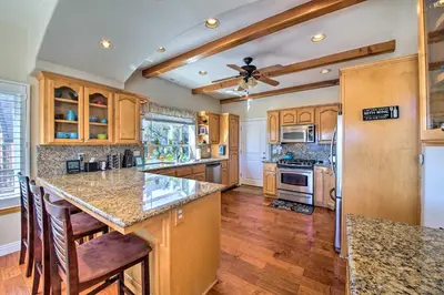a kitchen with wooden cabinets and a ceiling fan at Mountain Gem with Game Room, 5 Mi to Lake Arrowhead! in Lake Arrowhead