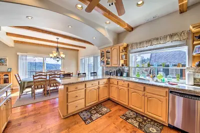 a kitchen with wooden cabinets and a dining room at Mountain Gem with Game Room, 5 Mi to Lake Arrowhead! in Lake Arrowhead