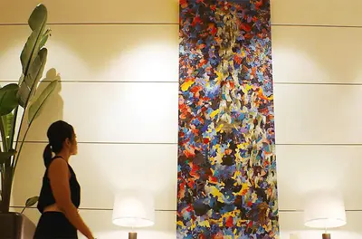 a woman walking past a large painting on the wall at Luskin Hotel in Los Angeles