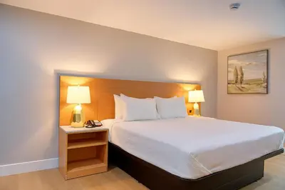 a bedroom with a large bed with two lamps on a table at Highland Inn - San Bernardino in Highland