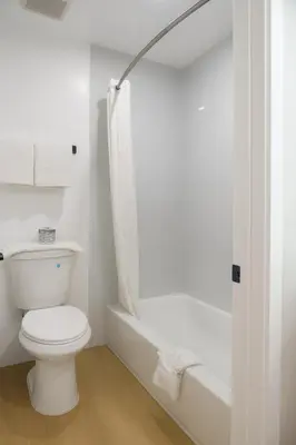 a white bathroom with a toilet and a shower at Highland Inn - San Bernardino in Highland
