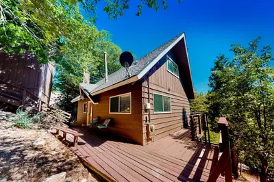 a cabin with a wooden deck with a bench on it at House of the Rising Sun in Lake Arrowhead