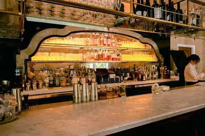 a bar with a woman standing behind a counter at Cara Hotel in Los Angeles