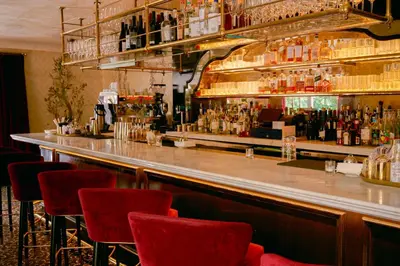 a bar with red chairs in a room with alcohol at Cara Hotel in Los Angeles