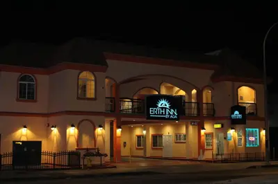a building with a sign that reads emmium at night at ERTH INN by AGA Maywood in Maywood