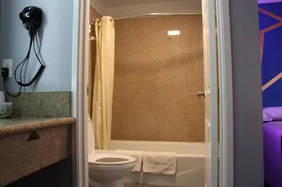 a bathroom with a toilet and a tub and a shower at ERTH INN by AGA Maywood in Maywood