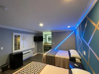 a blue room with two beds and a television at ERTH INN by AGA Maywood in Maywood
