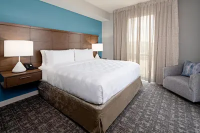 a hotel room with a large bed and a chair at Staybridge Suites - Long Beach Airport by IHG in Long Beach