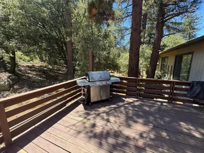 a barbecue grill sitting on a wooden deck at Quail Run Cabin 4,000 Sq.Ft Largest & Most Beautiful House On The Mountain in Pine Mountain Club